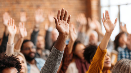 Participants express interest by raising hands during a lively discussion in a large venue.の素材