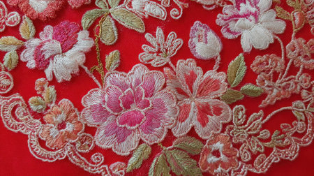 A red embroidered flower pattern with pink and gold flowers. The flowers are arranged in a circular pattern, and the embroidery is very detailedの素材