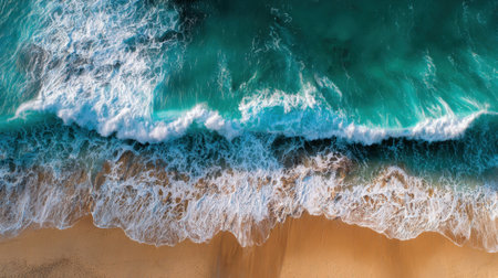 Bright turquoise waves roll onto a sandy beach, creating white foam as they crash. The scene captures a peaceful moment under a clear blue sky.の素材