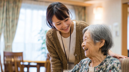 A caregiver interacts joyfully with an elderly woman in a nursing home. Their shared laughter and connection highlight the importance of companionship and care in daily life.の素材