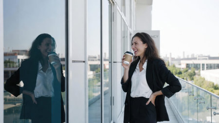 Young caucasian woman enjoying coffee on balcony in business attire.の素材