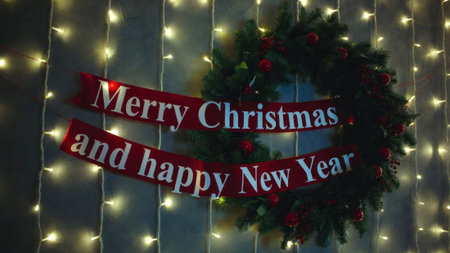 Festive christmas wreath and lights displaying holiday greetings.の素材
