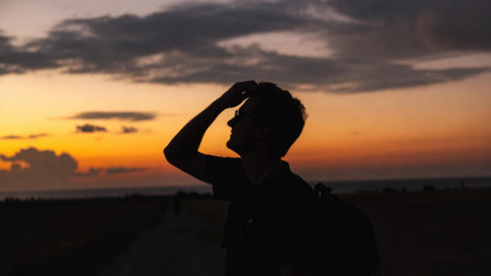 Silhouette of young caucasian male at sunset with dramatic sky.の素材