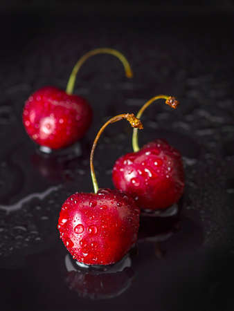 Beautiful cherry berries on a black background with water drops. Copy space.の写真素材