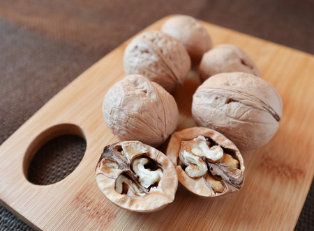 Walnuts on a bamboo cutting board on a dark brown background