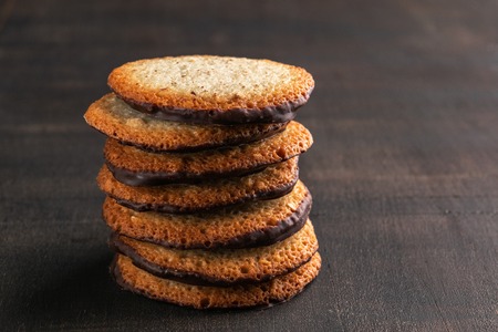 Biscuits filled with chocolate cream. Chocolate cream cookies. Chocolate covered cookies on dark rustic background. Copy space Horizontal.の写真素材