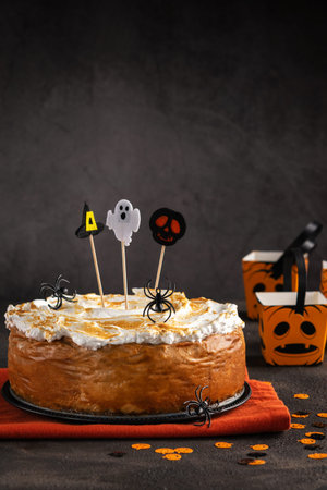 Halloween Party Pumpkin Cheesecake with Marshmallow Meringue Topping decorated with Halloween toppers. Dessert for Halloween and Thanksgiving Background. Space for text. Vertical. Selective focus.の写真素材