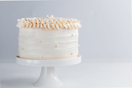 Beautiful Birthday Cake decorate with edible pearls on white neutral background. Copy space....