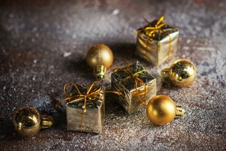 Christmas present mini golden boxes in the snow background. Close up. Christmas holiday celebration and new year concept. Winter holiday background. Vertical.の写真素材