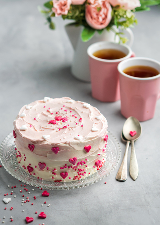 Birthday cake for Valentine's Day with pink hearts and colorful sprinkles. Valentine's day card background with copy space. Vertical.の写真素材