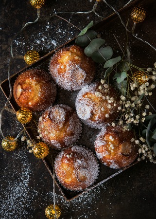 Homemade muffins with powdered sugar on a dark background, selective focus. Homemade bakery. Romantic concept. Top view.の写真素材