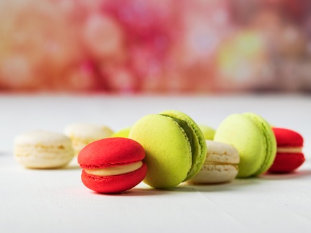 Sweet and colourful french macaroons on colorful spring background with copy space. Selective focus. Trendy coral color background. Spring happy concept. Horizontal.の写真素材