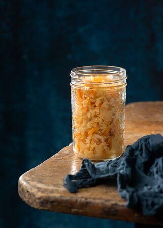 Homemade fermented cabbage kimchi sauerkraut, sour glass jars over rustic kitchen table, dark background, space for text. Fermented preserved vegetarian superfoods concept. Canned probiotic food .の写真素材