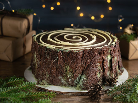 Chocolate tree stump cake with blurry christmas lights. Christmas and New Year holidays concept....