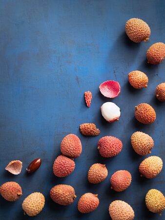 Lychee exotic fruits, organic, fresh and peeled showing the red skin and white flesh on trend classic blue color background, top view, space for text.の写真素材