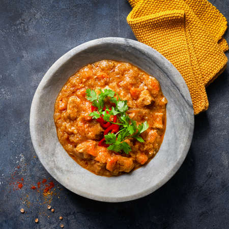 Indian food recipe. Chicken tikka masala spicy curry meat food in marble plate with spices and parsley on dark textured background with more empty space. Close up. Top view.の写真素材