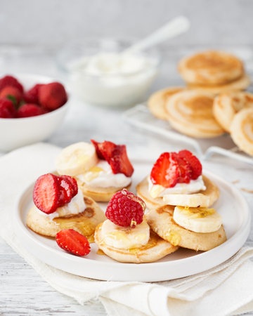 Golden delicious pancakes, honey, summer fruits on white wooden background with space for text. Romantic breakfast and traditional food for Shrove Tuesday. American cuisine, selective focus.の写真素材