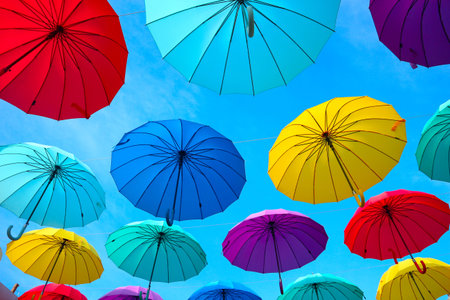 Bright multicolored umbrellas in the sky. Sun and rain protection on the street.