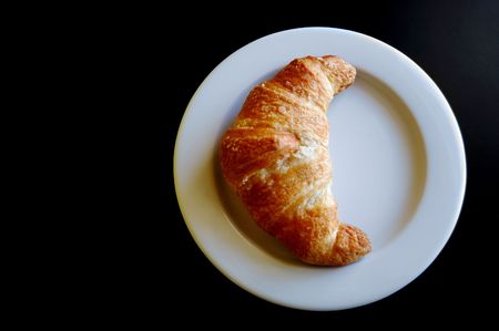 Croissant in a dish on black backgroung with copy spaceの写真素材