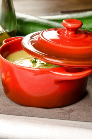 Cream of zucchini in a little casserole with croutons, oil and fresh vegetablesの写真素材
