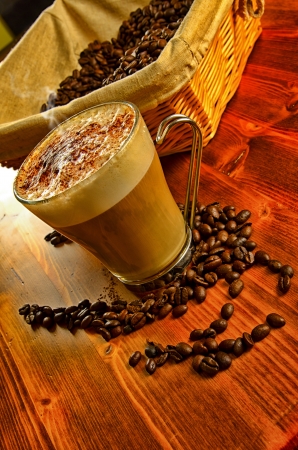 Italian cappuccino in a glass cup with coffee beans on backgroundの写真素材