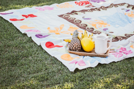 Picnic on the green grass in the park. On the blanket there is a basket of fruit.
