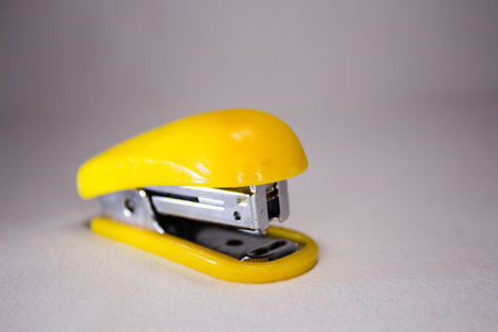 Yellow stapler for paper on a white background.