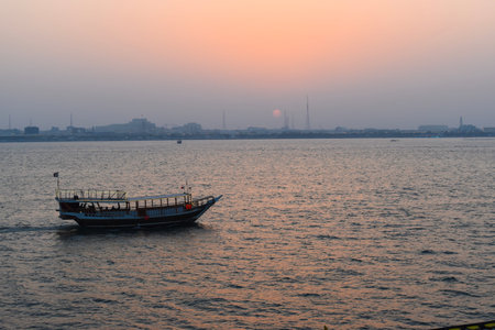Beautiful tranquil scene of a dhow boat on the calm sea in Doha, Qatar, at sunset.