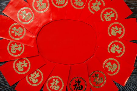 Chinese new year red envelope with wish around red background in dark wood. Top view