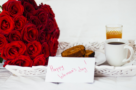 Breakfast in bed, celebrate valentines day, womens day or birthday. White bed, large bouquet of red roses. In the background of a pillow, a bedside table unfocus. copy space, free space.の写真素材