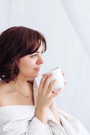 portrait Caucasian girl blanket bare shoulders coffeeの写真素材