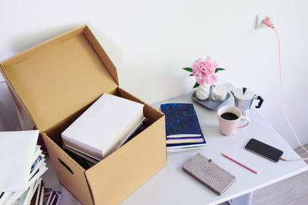 table with stationery, unpacking box with books. girl Back to college. Coffee, flowers, notebook