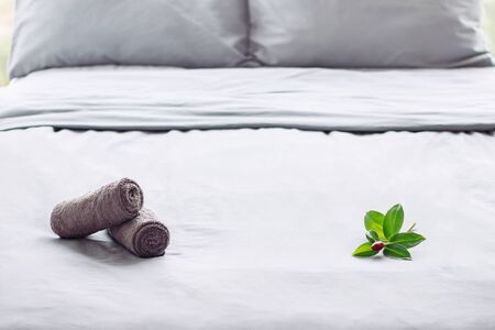 grey clean perfect bed, ready for guests, hotel room, towel, linens, backgroundの写真素材