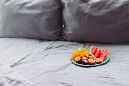 Plate with tropical fruit in grey bed, pilow backgroundの写真素材