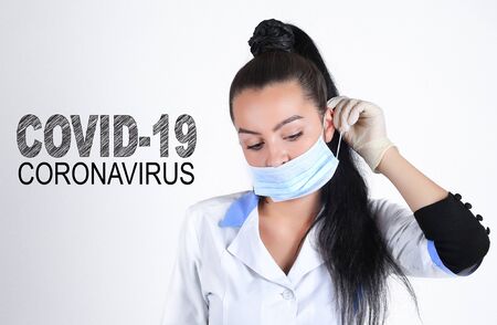Covid-19 coronavirus desease global pandemic outbreak. A young female doctor putting on medical mask.の写真素材