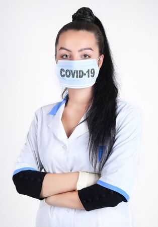 Covid-19 coronavirus desease global pandemic outbreak. A young female doctor in a medical mask with lettering. Novel virus prevention concept.の写真素材
