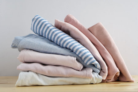 Stack of clothes. Jeans, shirt, dress, sweater on wooden table and white background isolation.