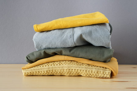 Stack of clothes on wooden table and grey background isolation
