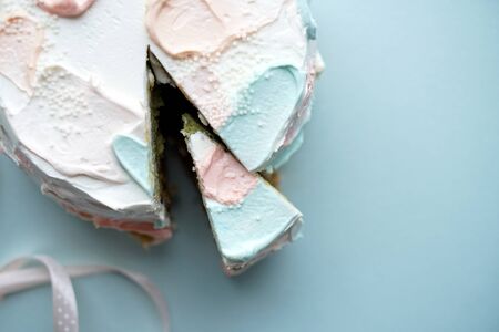 Birthday cake with a slice cut off on blue background Photoの写真素材