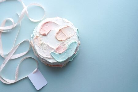 Birthday holiday cake with and pink ribbon with card on blue background. Photoの写真素材