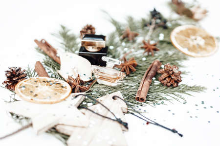 Christmas composition with evergreen tree branch, perfume bottle and other festive objects blurred on background. Photoの写真素材