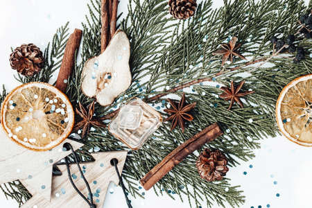 Christmas composition with evergreen tree branch, new year wooden toys, perfume bottles, dried fruits and plants. Photoの写真素材