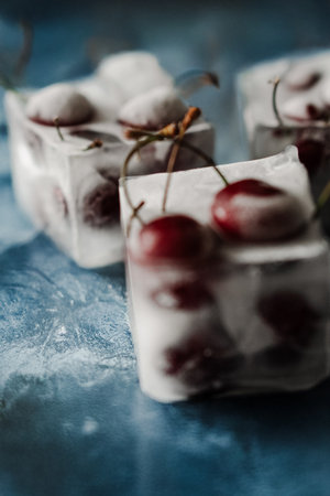 Fresh cherry in ice cubes on blue iced backgroundの写真素材