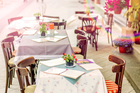 Background of blurred cafe on street of city. Tables and chairs outside in natural bokeh