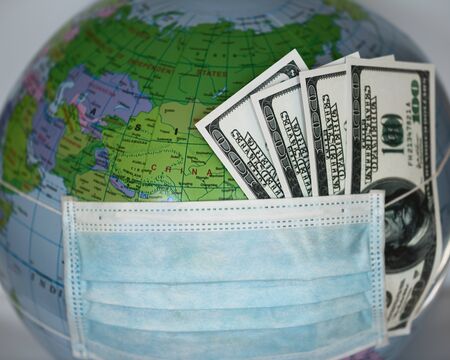 Globe with money covered with respiratory mask - Covid 19の写真素材