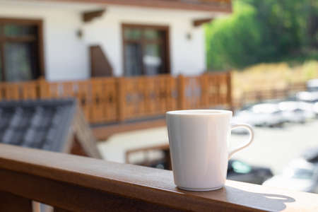 white mug with hot drink on a wooden terraceの写真素材
