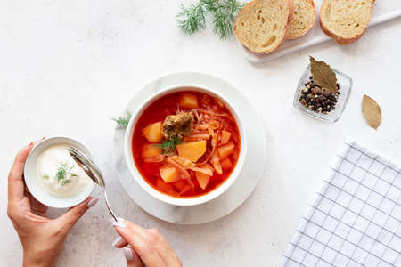 woman eating red borscht with vegetables, meat and sour creamの写真素材
