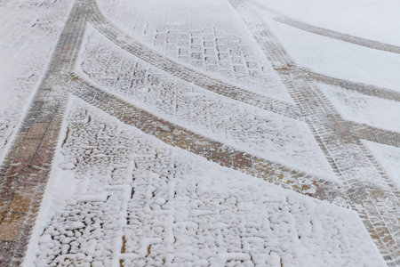 curved tire tracks in the snow on a cobblestone road.