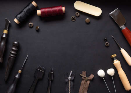 set of tools for sewing leather goods on black leather background.の写真素材