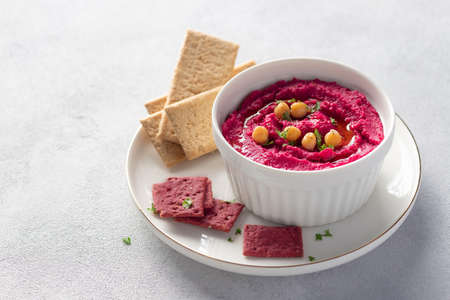 beetroot hummus in white bowl with chickpeas and crackersの写真素材